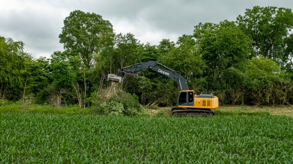Excavator removing overgrown brush and vegetation in a field, illustrating ADX Excavating's brush removal services near Souderton, PA.