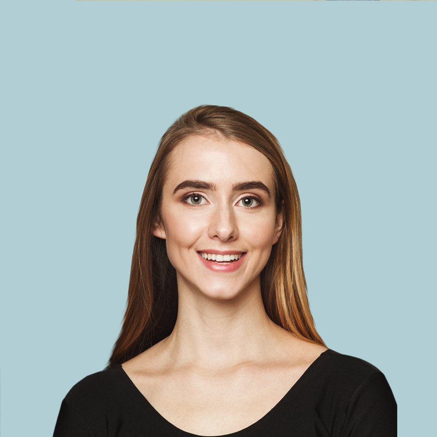 Smiling woman with long hair in a black top against a light blue background, representing customer satisfaction and professional service in grading and excavation.