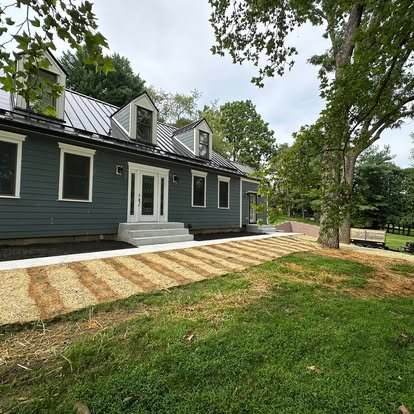 Newly graded residential property with temporary erosion control matting, mulch coverage, and prepared soil for quick-germinating annual ryegrass, emphasizing spring grading for effective drainage and erosion prevention.