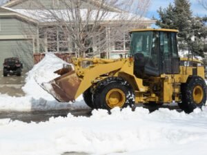 Snow removal equipment clearing snow from residential driveway, emphasizing winter property management in Pennsylvania.