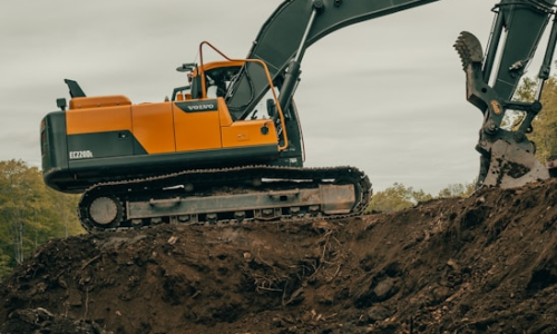 Excavator on a dirt mound, showcasing land clearing and grading capabilities relevant to ADX Excavation's forestry mulching services in Souderton, PA.
