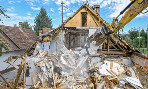 Demolition of a residential structure with excavator breaking down walls and debris, showcasing the process of site clearing and preparation for new construction.